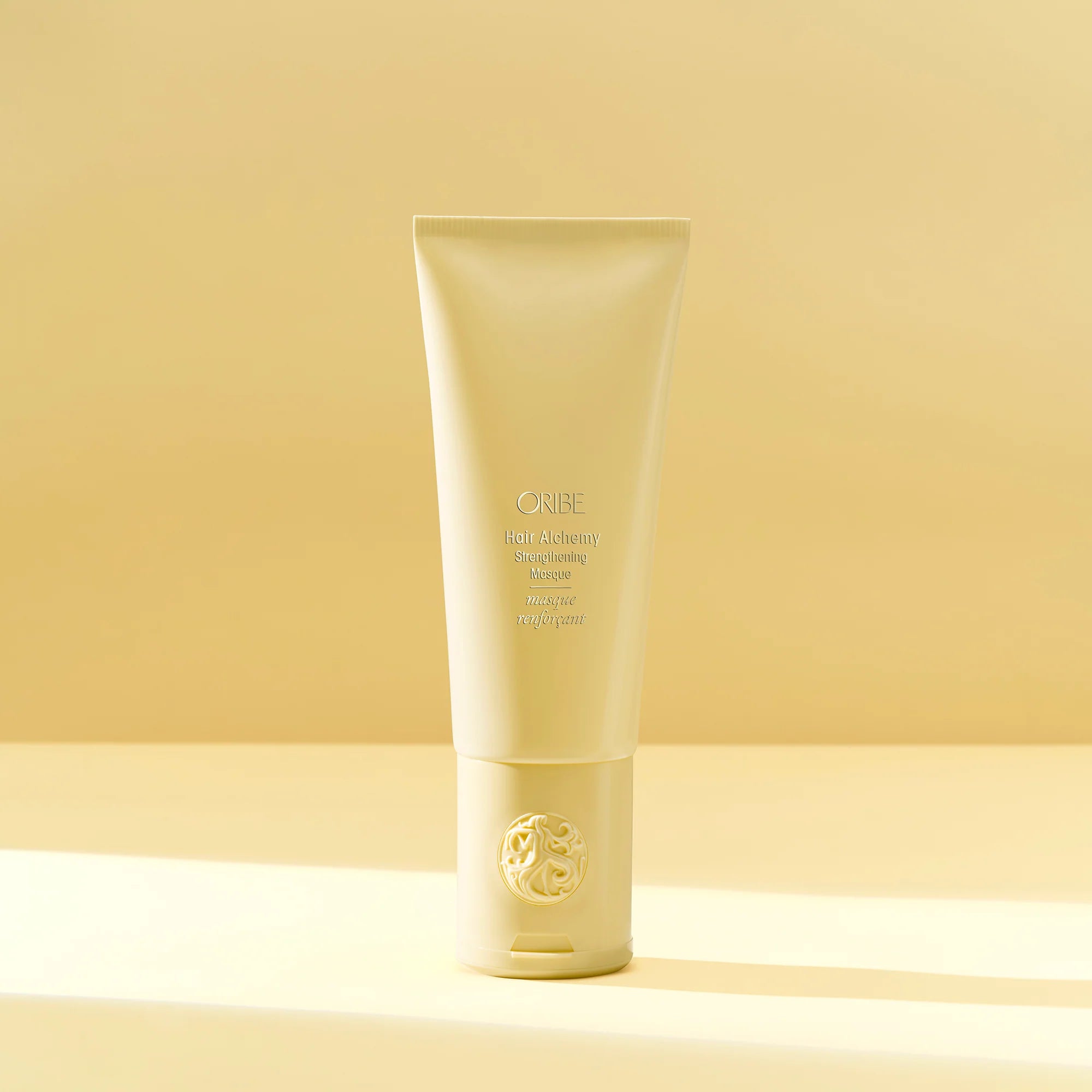 A tube of Oribe Hair Alchemy Strengthening Masque, designed for fragile or breakage-prone hair, against a neutral background.