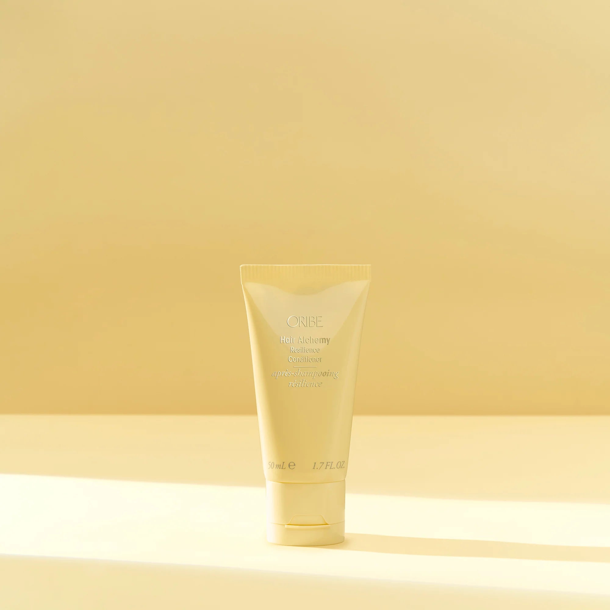 A yellow tube of Oribe Hair Alchemy Resilience Conditioner.