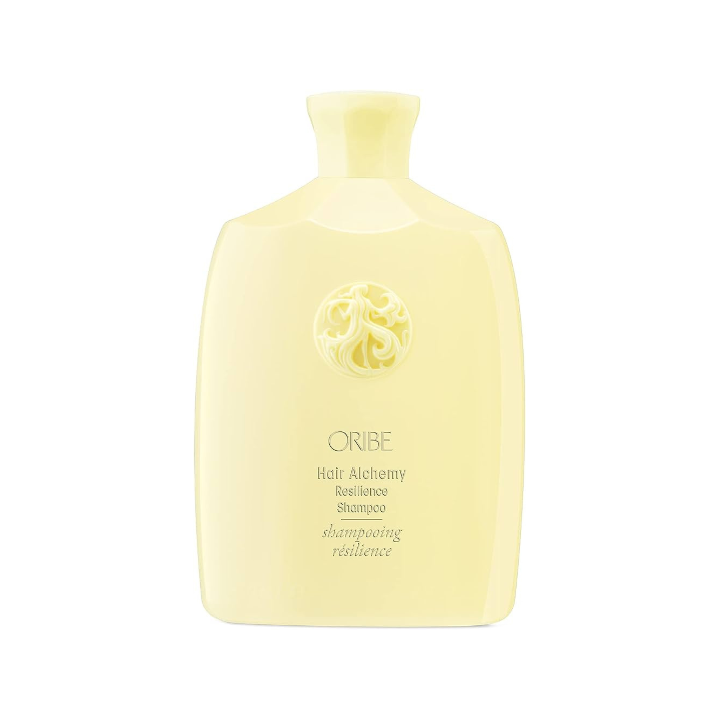 A pale yellow bottle of Oribe Hair Alchemy Resilience Shampoo with a floral design near the cap.