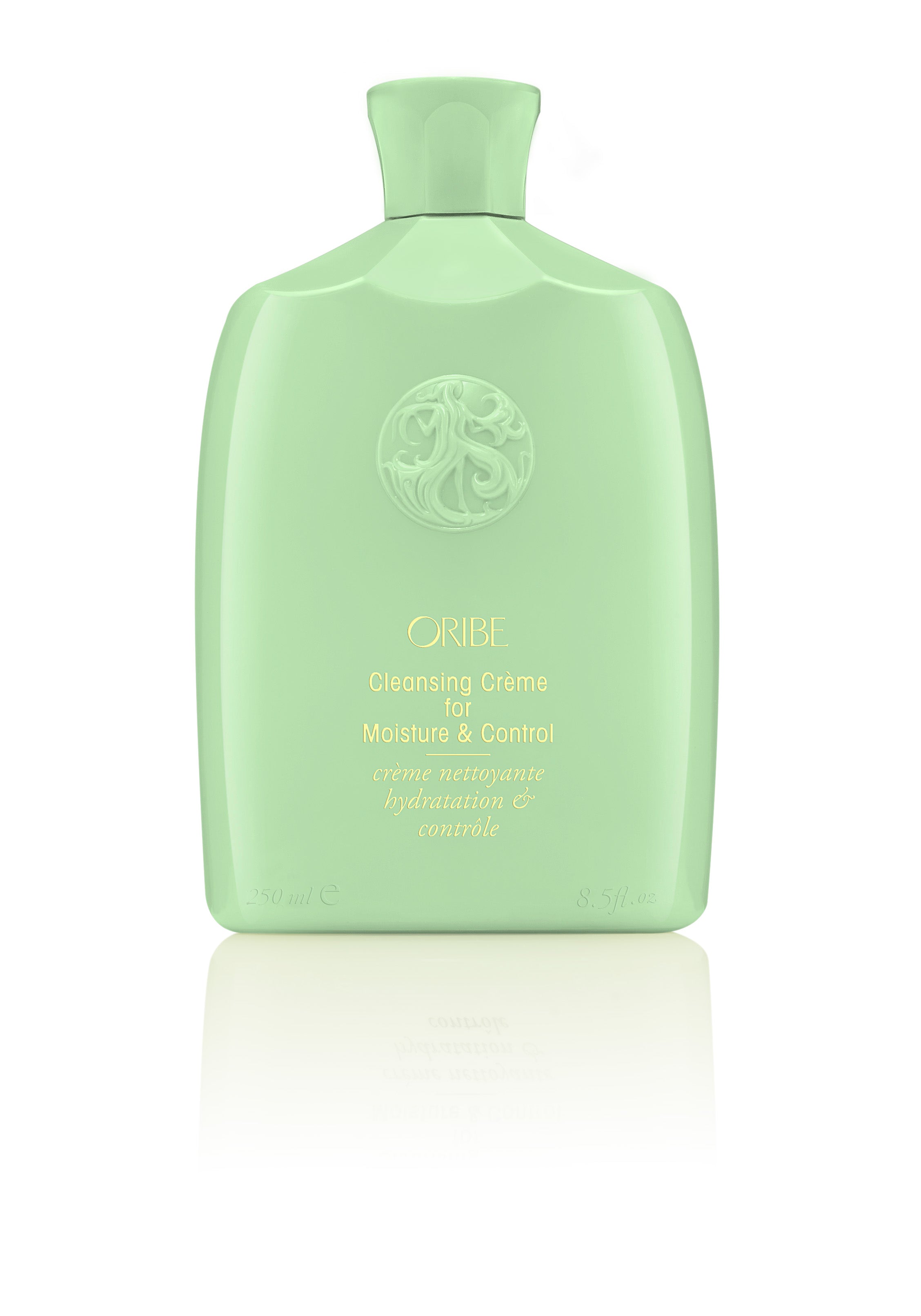 A bottle of Oribe Cleansing Crème for Moisture and Control with a green label and cap.