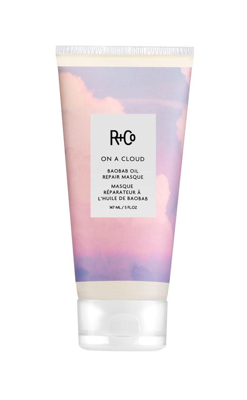 A tube of R+Co On A Cloud Baobab Oil Repair Masque with a purple and pink cloud design.