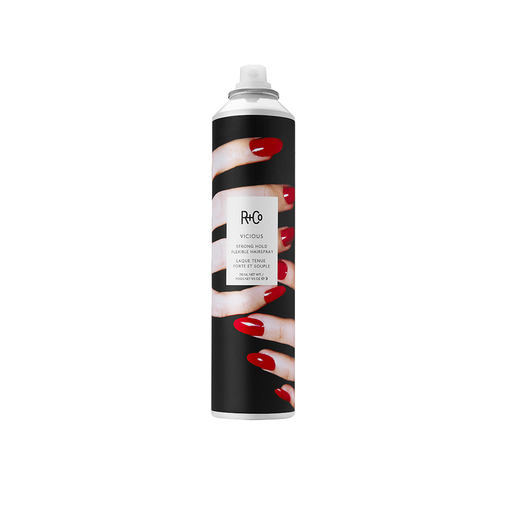 A can of R+Co Vicious strong hold flexible hair spray with a black background and white text, featuring an image of red fingernails.
