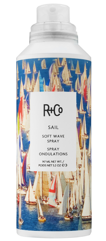 Bottle of R+Co Sail Soft Wave Spray with sailboats and a blue sky printed on the label.