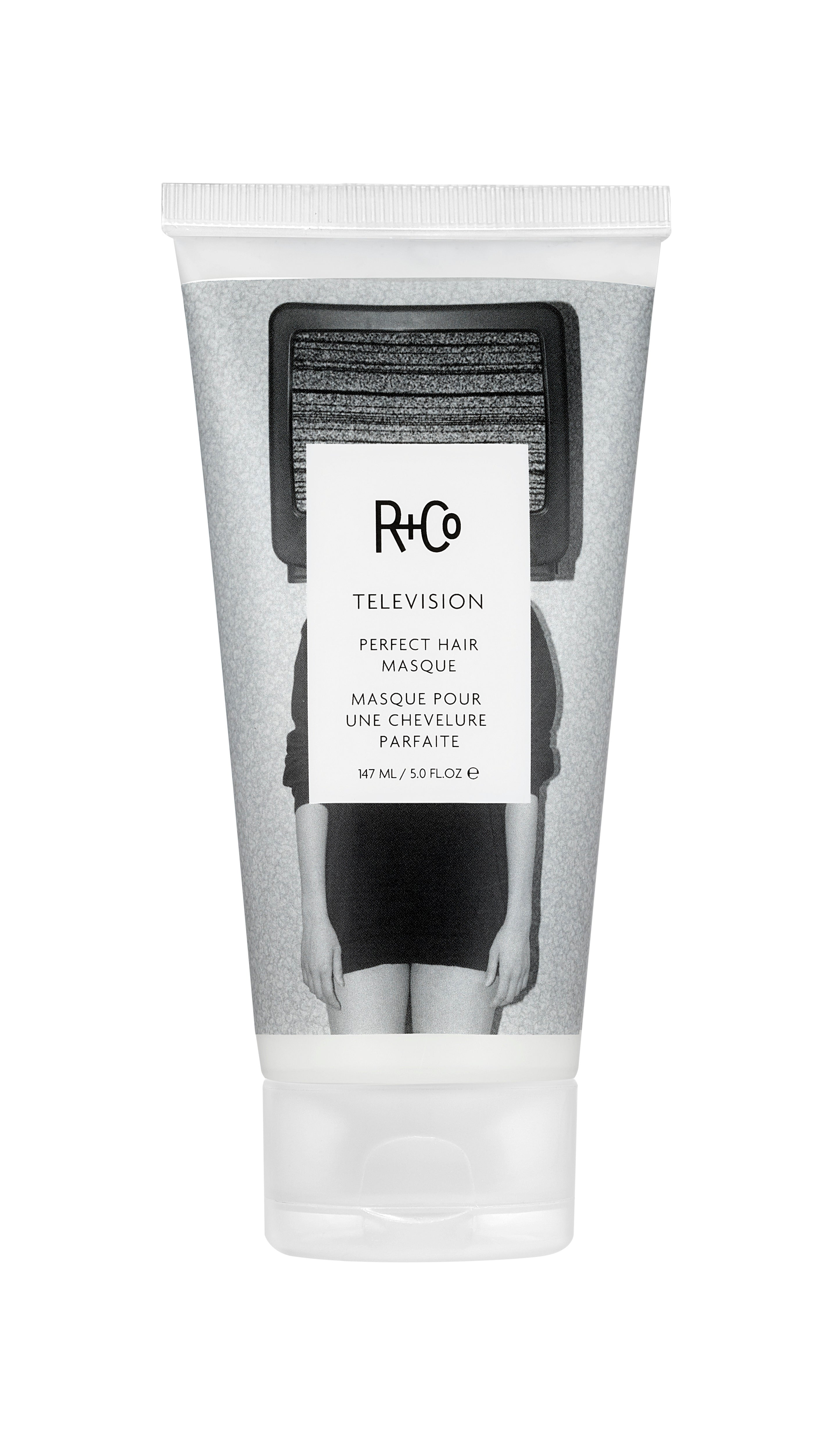 A tube of R+Co Television Perfect Hair Masque, primarily gray and black in color with product details in French.