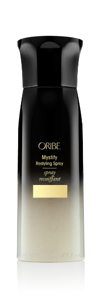 A black bottle of Oribe Mystify Restyling Spray with a white label and gold accents.